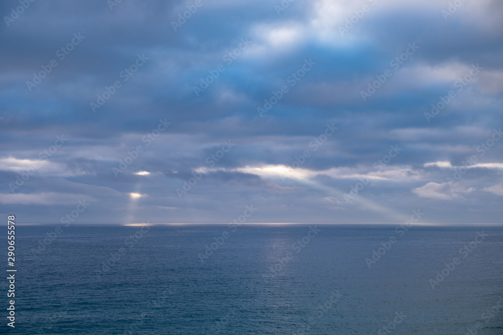 Sun rays shinning through the clouds above the horizon of the sea on a cloudy day in England, UK.