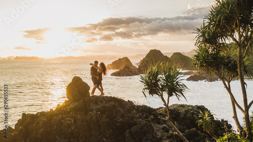 Couple enjoying sunset with amazing ocean and mountain view. Travel concept, panoramic shot, wanderlust.