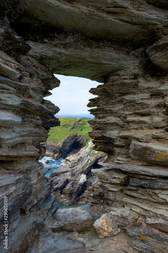 The a window from ruins of King Arthur’s Castle provides a view of the green and rocky cliffs that overlook the sea.