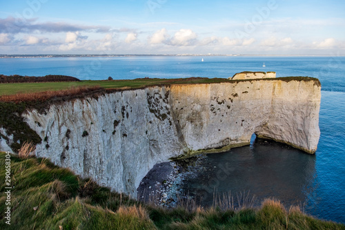 Famous white chalk cliffs called Old Harry Rocks overlooking the sea on partially cloudy day in England, UK.