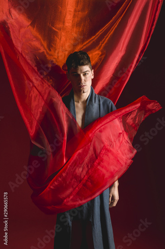Boudoir shot of man in robe with red background