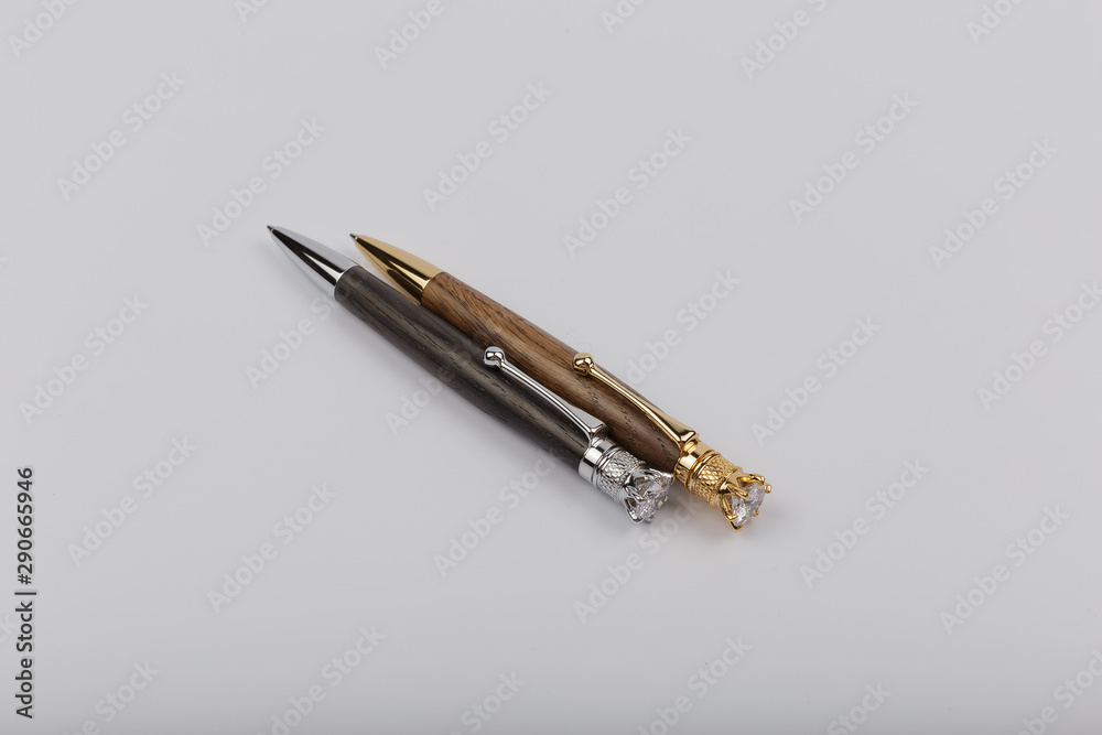 Two handmade ballpoint pens made of wood and metal on a white background. Two handmade ballpoint pens made of wood and metal on a white background.