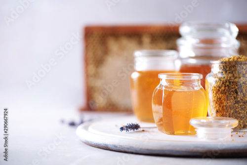 Honey products background. Honeycomb frame, bee pollen granules, honey in glass pot on grey concrete background. Copy space. Autumn harvest concept.