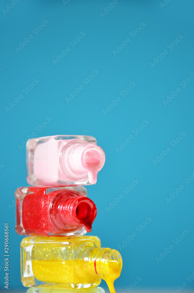 Bottles with spilled nail polish over blue background The concept of fashion, beauty, women's care. manicure. beauty saloon. spa Bottles with spilled nail polish over blue background The concept of fashion, beauty, women's care. manicure. beauty saloon. spa