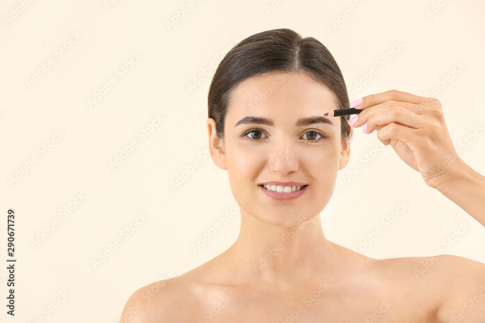 Young woman undergoing eyebrow correction procedure on light background Young woman undergoing eyebrow correction procedure on light background