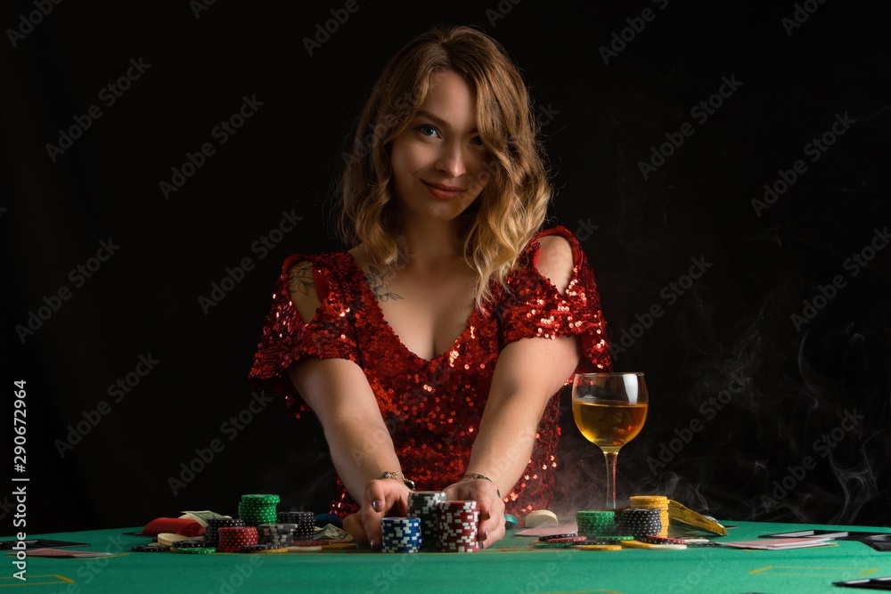 Girl in evening red dress plays poker. Gaming business in a casino or night club. On a black background for design, with smoke. Girl in evening red dress plays poker. Gaming business in a casino or night club. On a black background for design, with smoke.