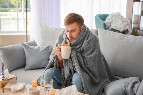 Sick man drinking hot tea at home photo