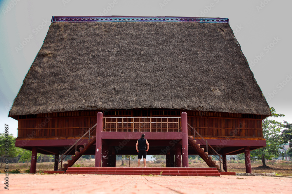A tourist exploring a traditional architecture of a Bahnar ethnic stilt
