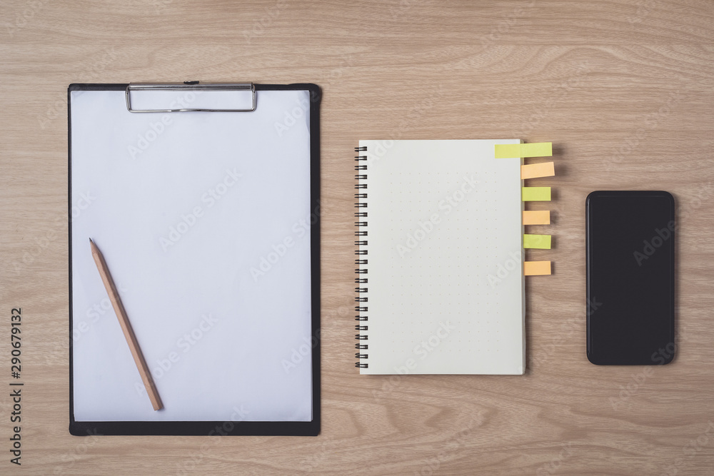 Workspace with diary or notebook and smart phone, clipboard, pencil, sticky notes on wooden background