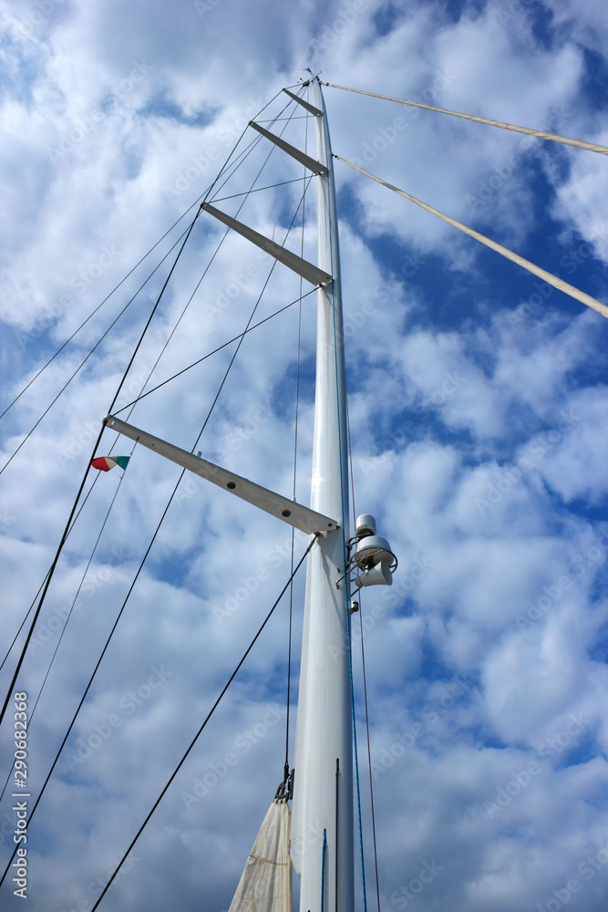 Yacht mast with Italy flag at blue sky background with clouds. Good weather for sailing. Vertical view. Yacht mast with Italy flag at blue sky background with clouds. Good weather for sailing. Vertical view.
