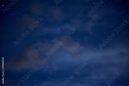 Night starry sky. Bright stars and constellations are visible through light clouds.