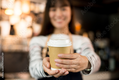 Young asian women barista hold coffee cup serving a client at the coffee shop start up small business owner food and drink concept..