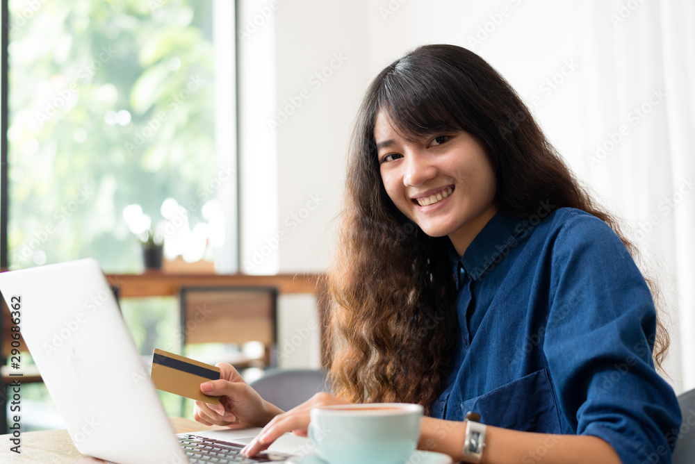 Young woman or student using laptop and shoping online sitting at coffee shop. Happy girl working online or studying and using notebook. Freelance business concept. Young woman or student using laptop and shoping online sitting at coffee shop. Happy girl working online or studying and using notebook. Freelance business concept.