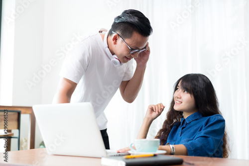 Young woman and man or student using laptop sitting at coffee shop. Happy girl working online or studying and using notebook. Freelance business concept.