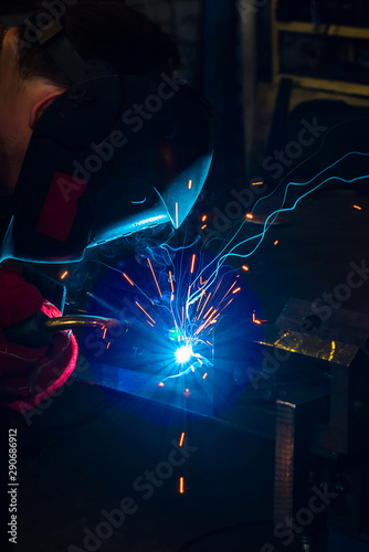 Welder in the mask makes the metal. Close up. Sparks from welding.