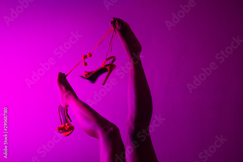 Red or orange high heels shoes and sexy black woman legs on pink background.