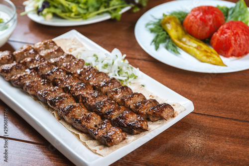 Fast food. Eastern food. Shish kebab, lyulya-kebab. Dishes of oriental cuisine lying in plte and decorated with greens and vegetables, sauces photo