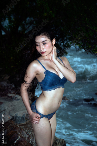 Canvas Print Pretty Asian woman in blue bikini posing on the beach with fun.