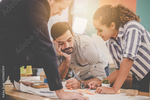 Three Young Creative Marketeer is brainstorming on business data on the table, Two creative designer in a discussion for business and creativity success concept.