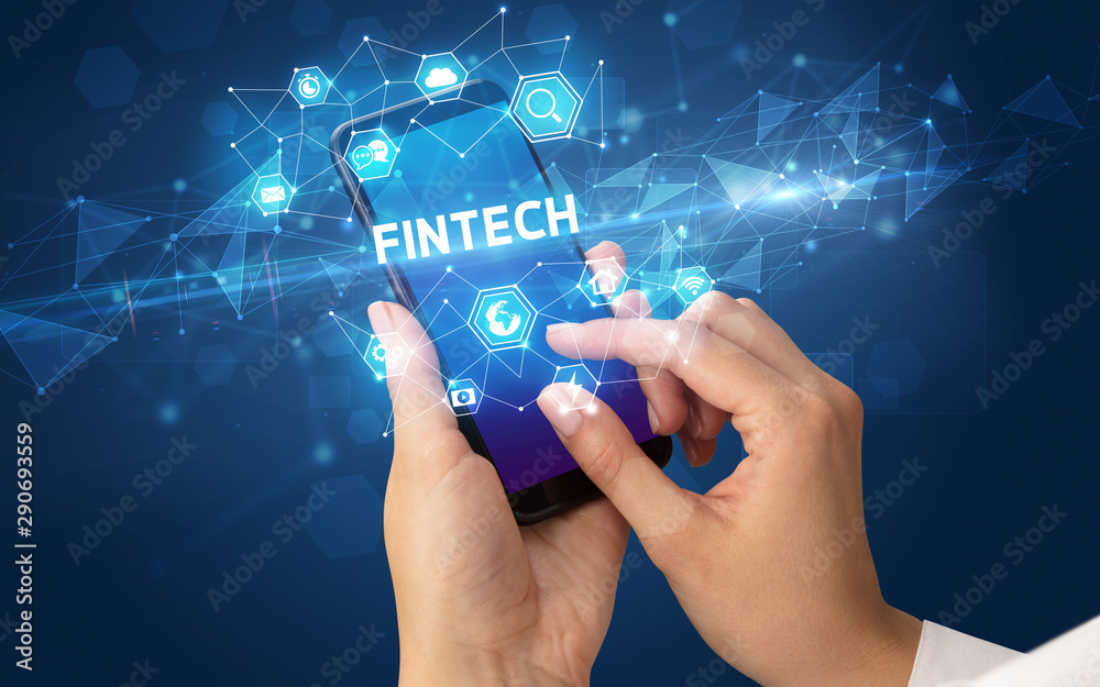 Female hand holding smartphone with FINTECH inscription, modern technology concept Female hand holding smartphone with FINTECH inscription, modern technology concept