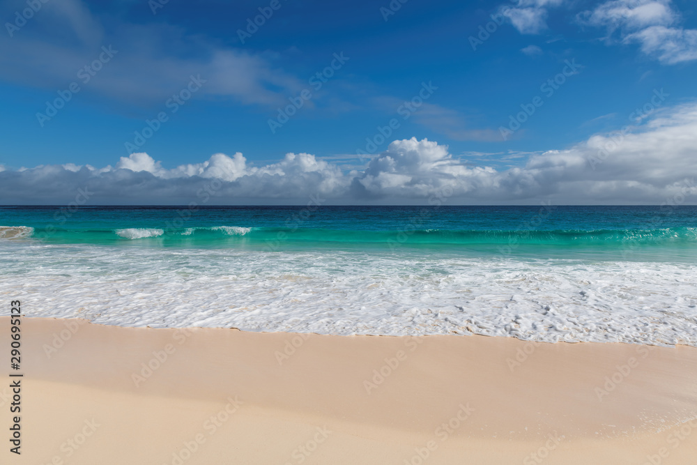 Ocean wave in sandy beach on tropical island background, copy space.