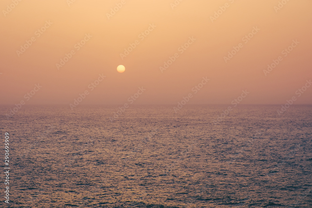 Fototapeta premium sunset on water, sun going down behind ocean