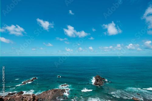 Blue sky above ocean horizon on sunny summer day at rocky coast