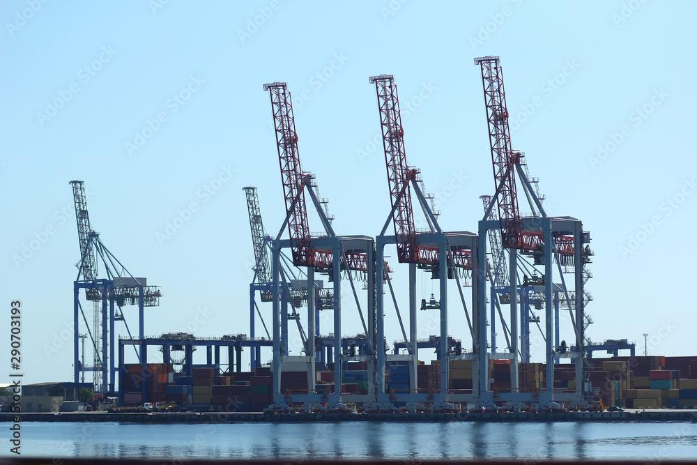 Industrial view of sea port warehouse, container spreaders and gantry cranes. Import export, global logistics concept.