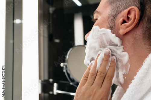 Close-up of man applying shaving foam on his face. photo