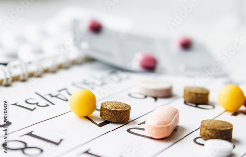 Pills, supplements and medicines for the disease. A pile of different pills on a calendar background.