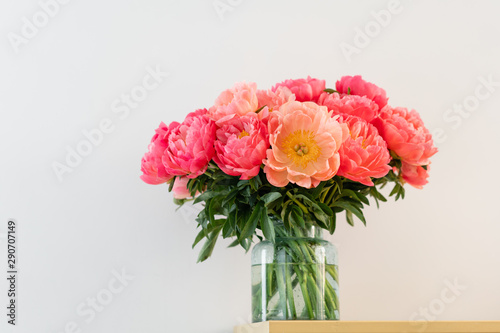 Coral peonies in a glass vase on wooden table.. Beautiful peony flower for catalog or online store. Floral shop concept . Beautiful fresh cut bouquet. Flowers delivery. Copy space