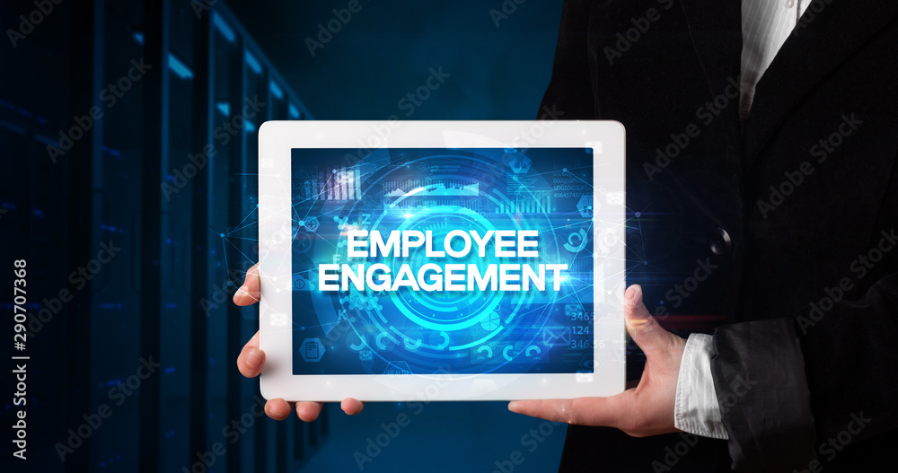 Young business person working on tablet and shows the inscription: EMPLOYEE ENGAGEMENT, business concept Young business person working on tablet and shows the inscription: EMPLOYEE ENGAGEMENT, business concept