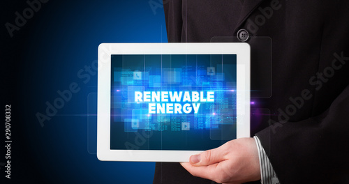 Wallpaper Mural Young business person working on tablet and shows the inscription: RENEWABLE ENERGY Torontodigital.ca