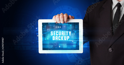 Wallpaper Mural Young business person working on tablet and shows the digital sign: SECURITY BACKUP Torontodigital.ca