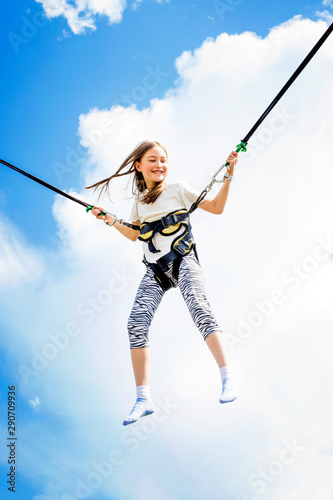 Little girl bouncing high in the air using a bungee trampoline.