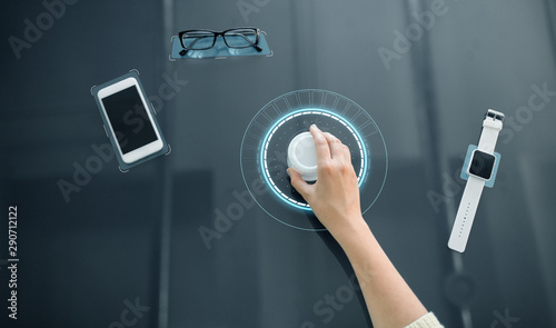 technology and people concept - close up of woman's hand using rotary control knob on interactive panel with virtual hologram
