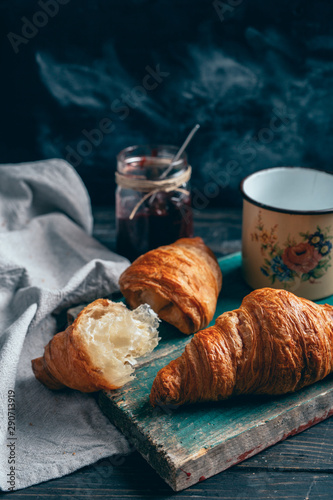 croissants and plum jam on rustic wooden board