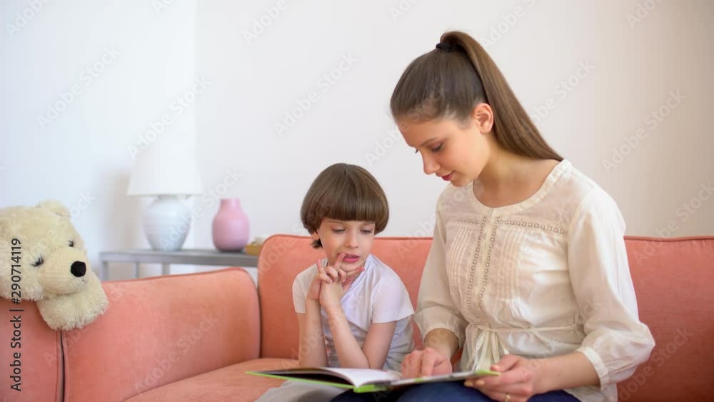 Mother and son reading books. Happy young mother and little boy child read books on sofa at home room. motherhood, home schooling. education, happy family 4 K Mother and son reading books. Happy young mother and little boy child read books on sofa at home room. motherhood, home schooling. education, happy family 4 K