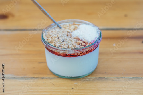   "Malabi" on a wooden table - "Malabi" is  the Israeli ultimate dessert ! milk pudding that served with rose water and sugar syrup , nuts and grounded coconut. 