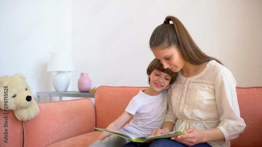 Mother and son reading books. Happy young mother and little boy child read books on sofa at home room. motherhood, home schooling. education, happy family 4 K Mother and son reading books. Happy young mother and little boy child read books on sofa at home room. motherhood, home schooling. education, happy family 4 K