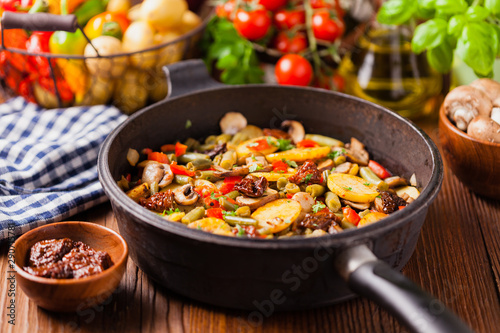 Fried pan vegetables  with mushrooms and dried tomatoes. Seasoned with a mix of herbs.