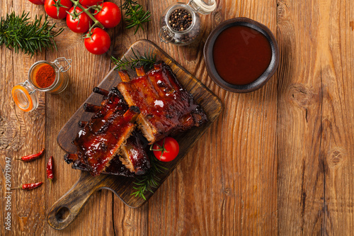 Roasted pork ribs in a bbq sauce. Served on a wooden board. Top view.