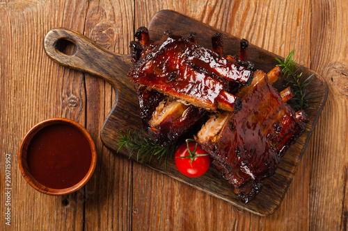 Roasted pork ribs in a bbq sauce. Served on a wooden board. Top view.