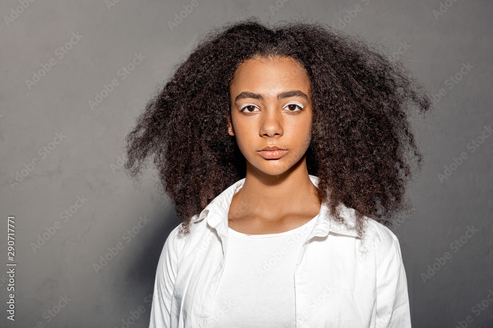 Freestyle. African girl in white outfit standing isolated on gray looking camera indifferent lighted close-up Freestyle. African girl in white outfit standing isolated on gray looking camera indifferent lighted close-up