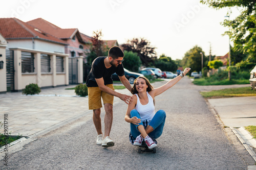 happy couple outdoor having fun riding skateboard