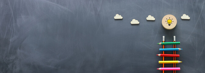Education concept of Ladder made from pencils next to clouds over blackboard