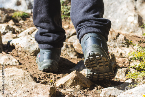 Person walking in the countryside with hiking boots between stones and plants