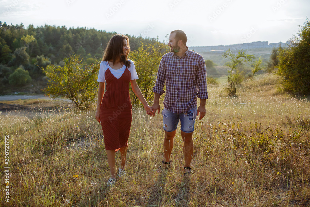 Beautiful couple holding hands on a field at sunset.