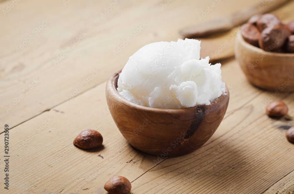 Shea butter in wooden bowl with nuts on old rustic table. Free text space. Shea butter in wooden bowl with nuts on old rustic table. Free text space.