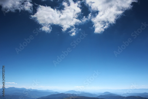 Mountains on the horizon and a blue sky with clouds © valkoinen7